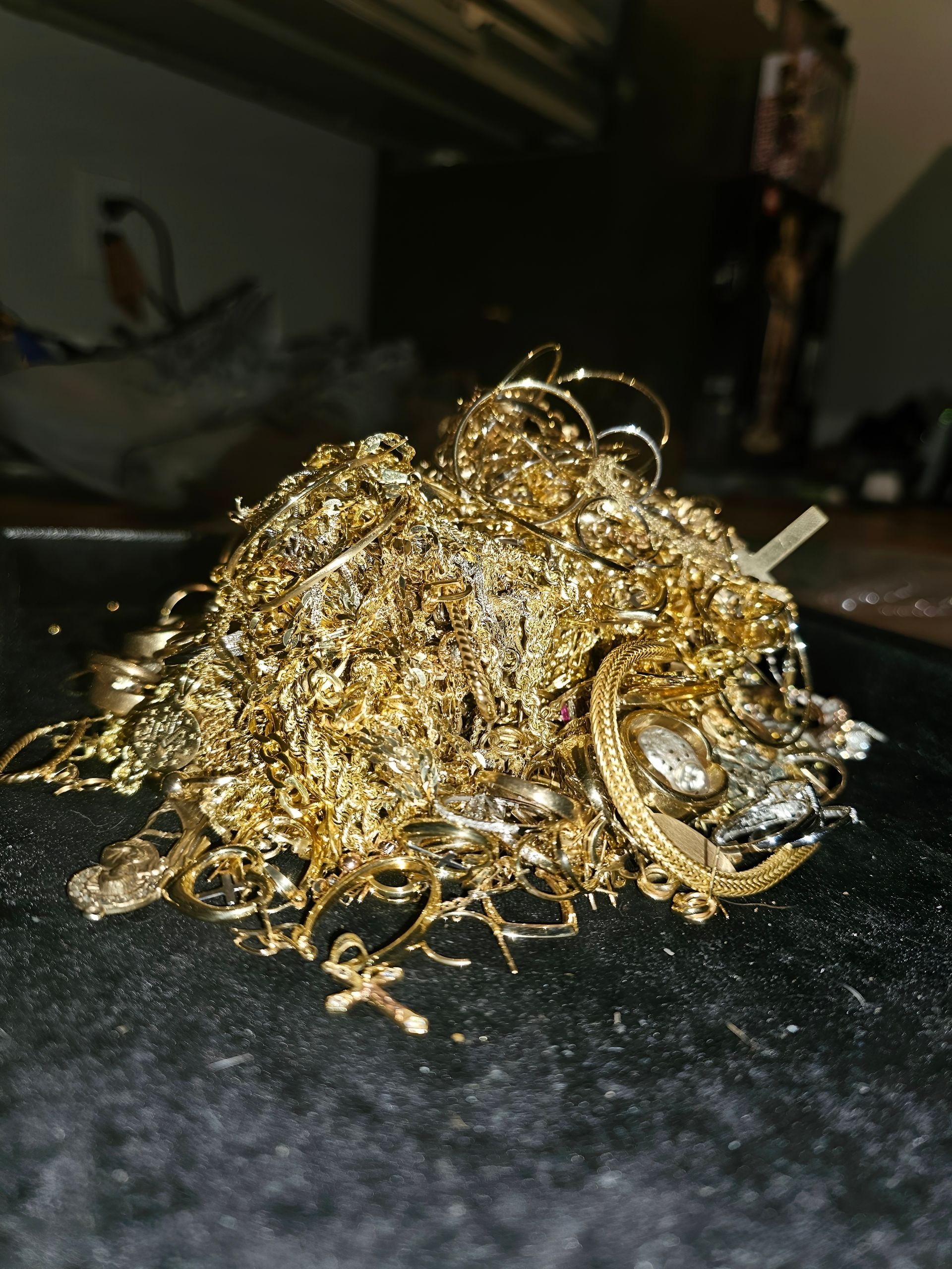 A tangled pile of gold chains and jewelry on a dark surface