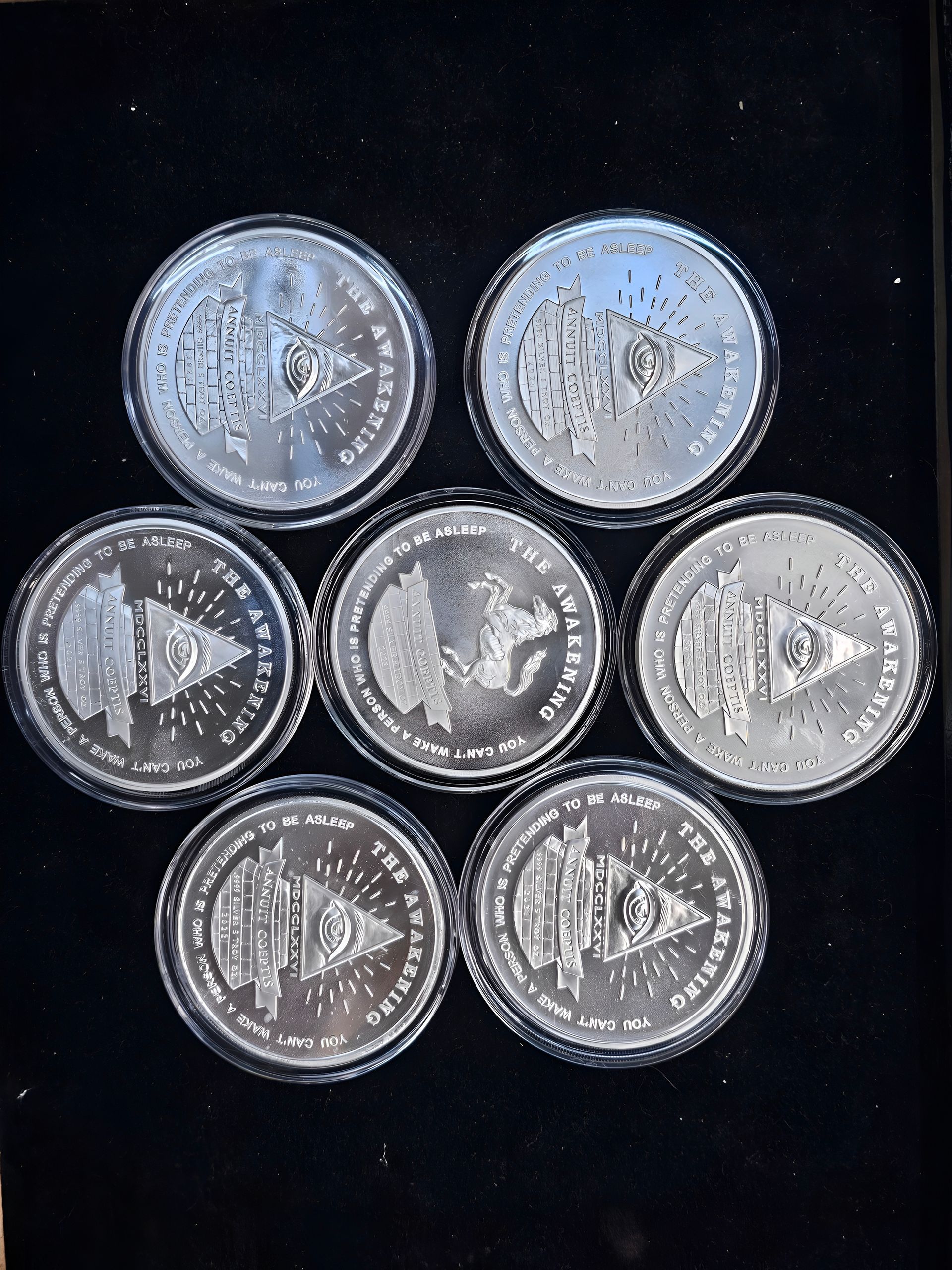 Seven silver coins arranged in a flower shape on a black background