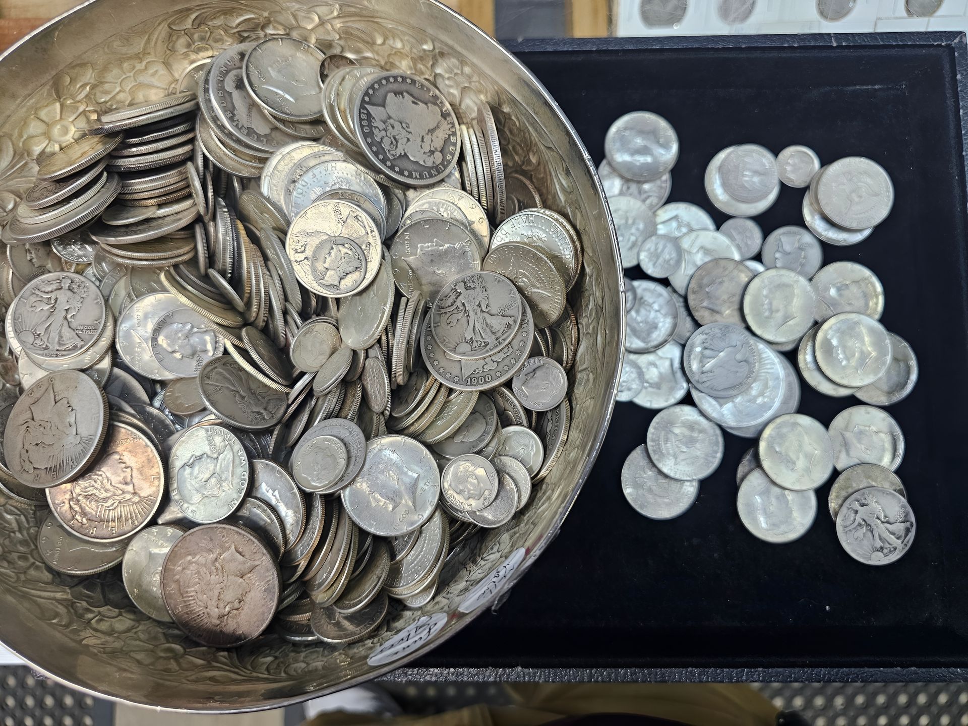 A bowl and tray filled with stacks and loose silver coins