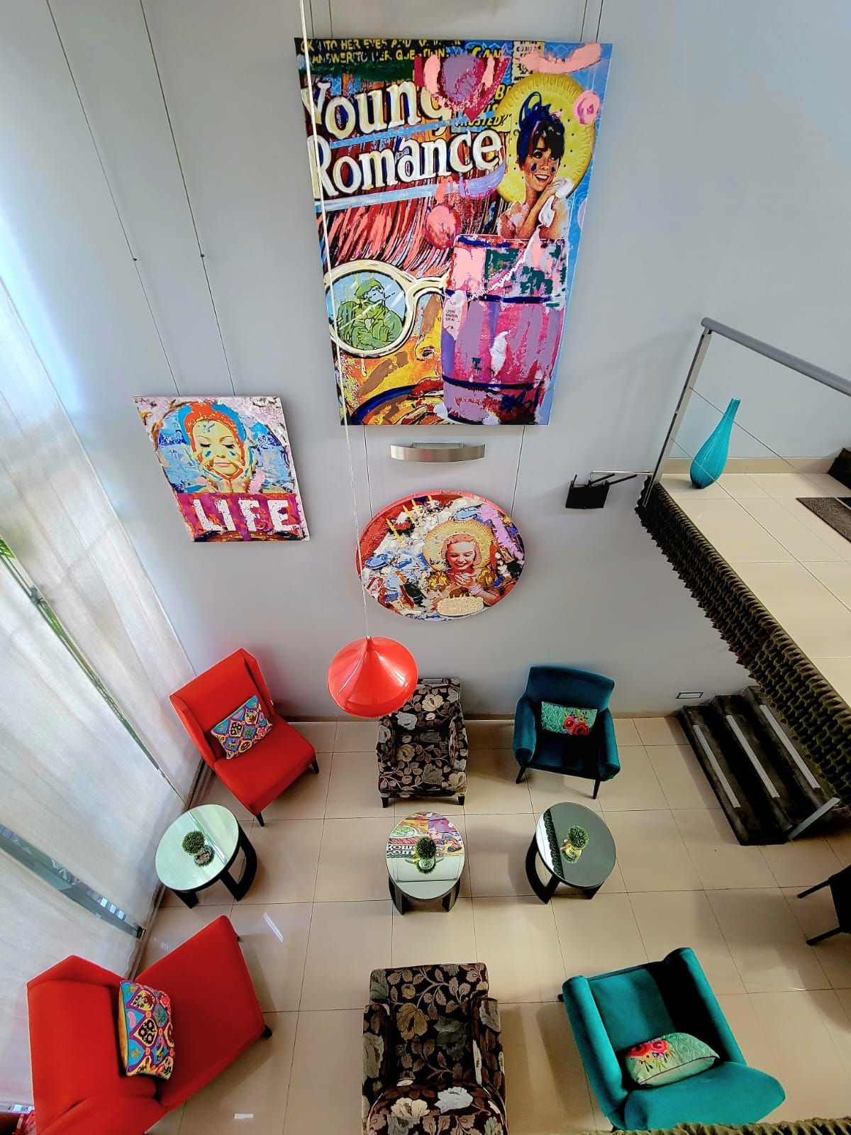 Dollhouse bedroom display with colorful mini chairs, posters, and small furniture on a white floor