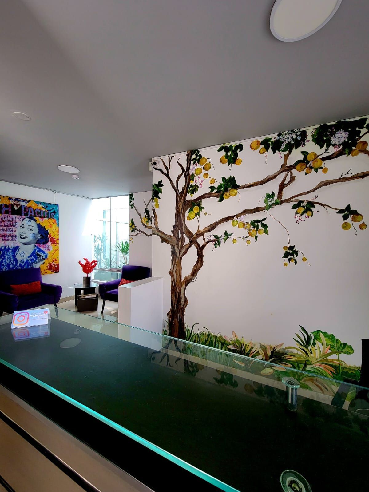Modern indoor patio with stone table, bar stools, stairs, and colorful wall art by a window