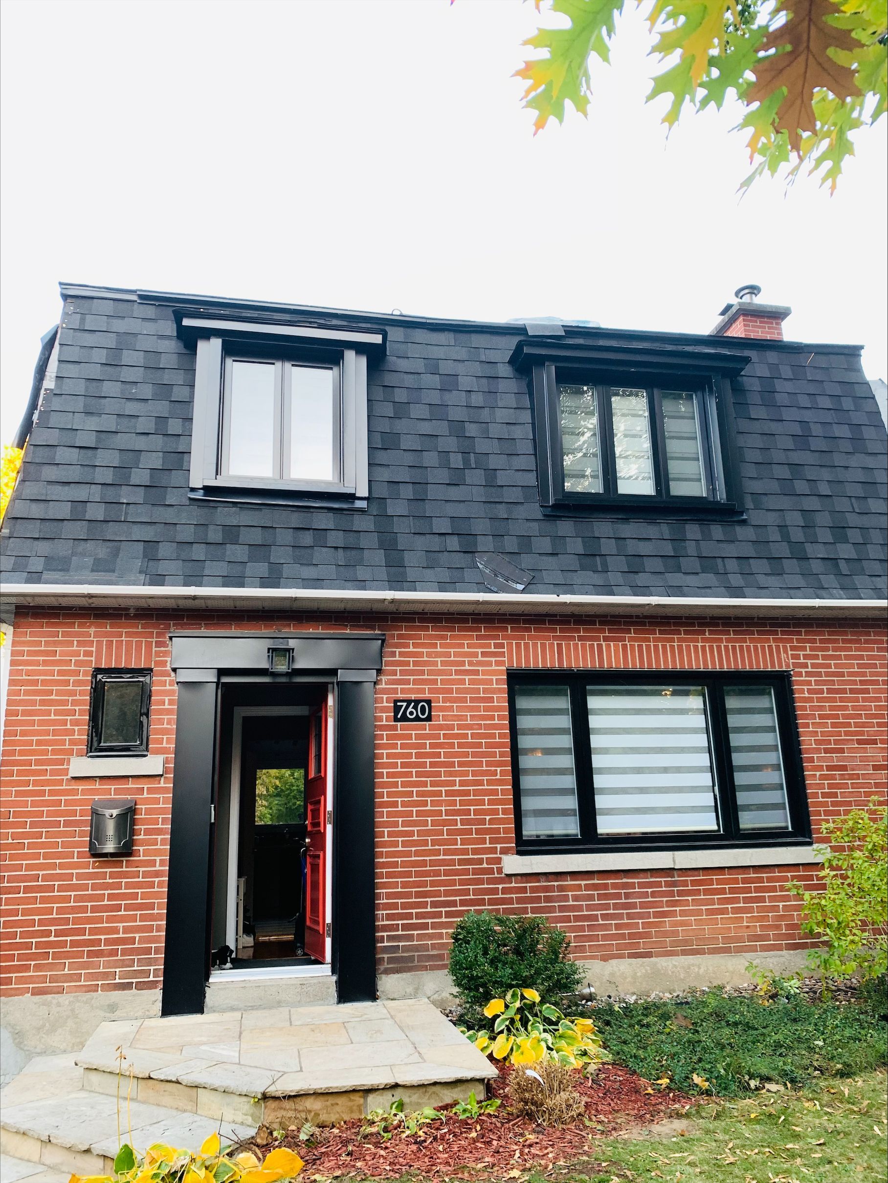 Une maison en brique avec un toit et des fenêtres noirs