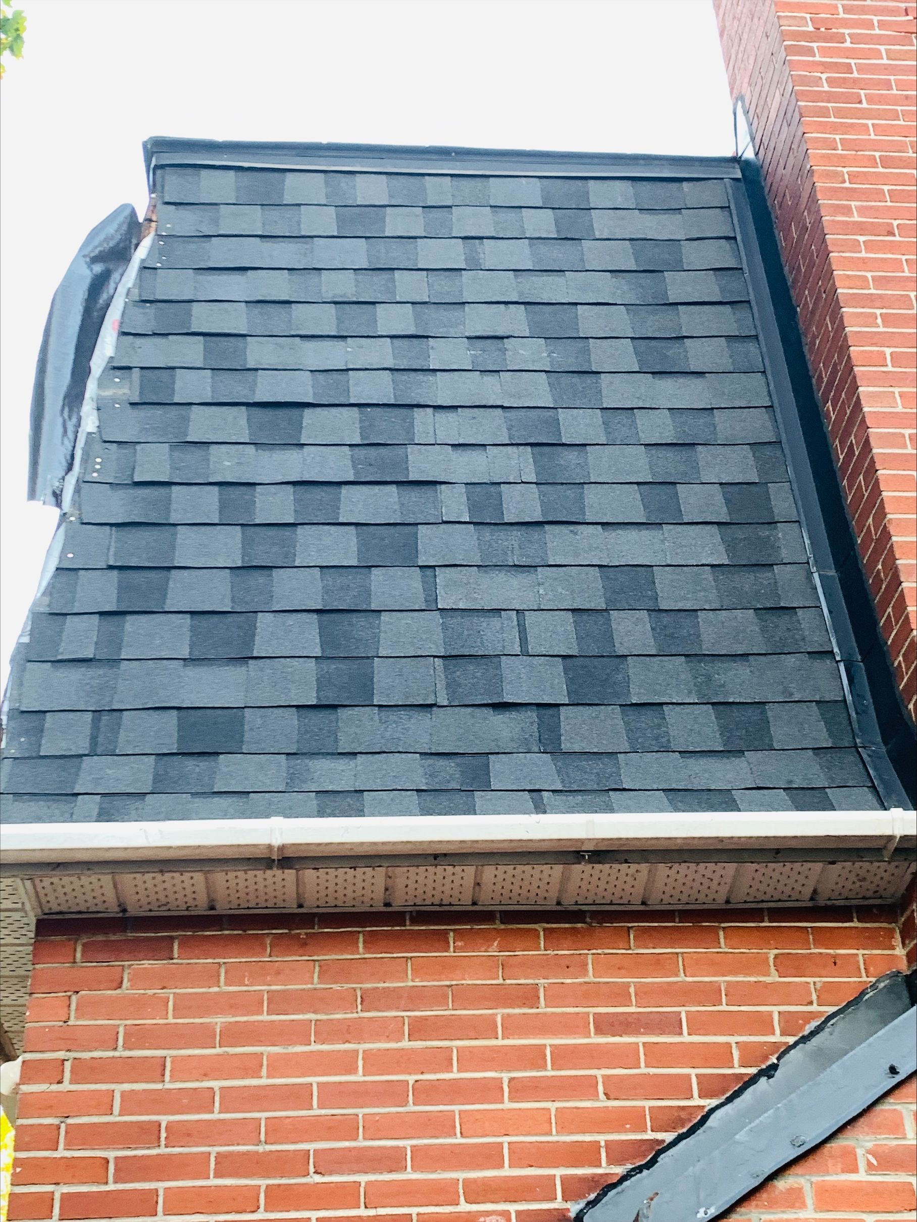 Un bâtiment en briques avec un toit noir et une cheminée.