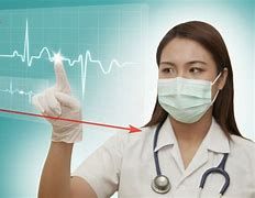 A medical professional in a white coat and mask touches a digital screen displaying an EKG heart rate monitor.