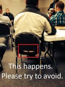 A man sits in a chair with a hole in the back that says this happens please try to avoid