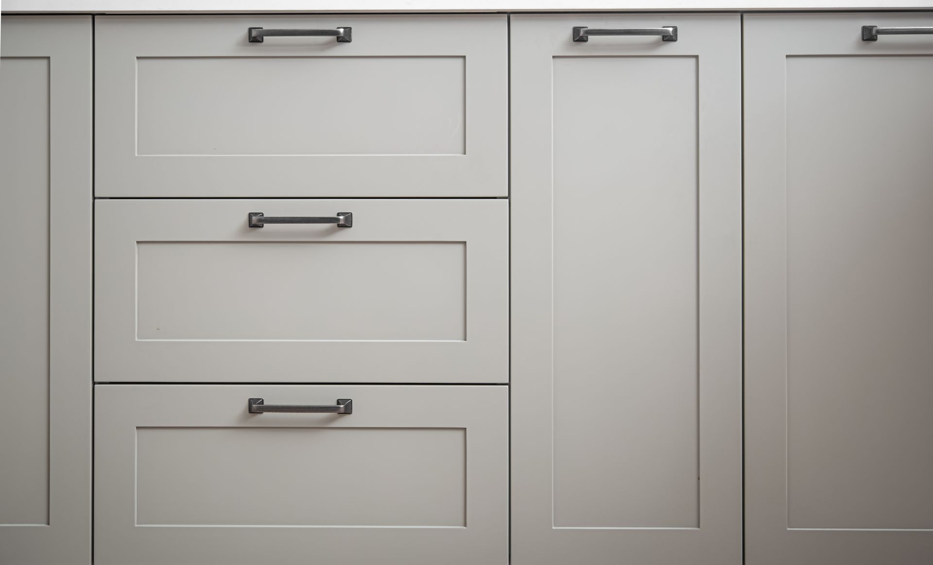 Gray kitchen cabinets with black handles.
