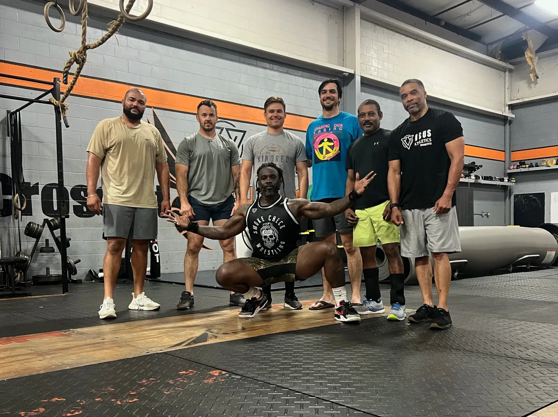 Group posing in a gym, with one person crouching front and five standing behind them.