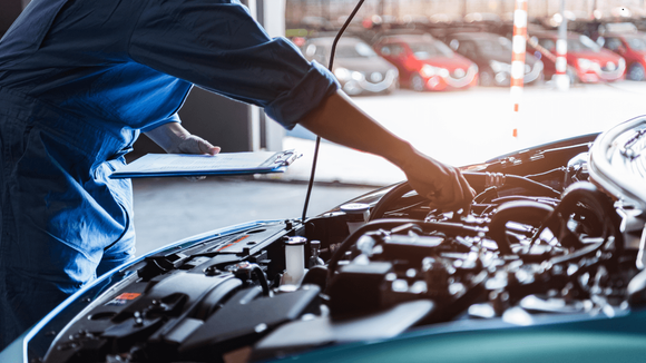 A mechanic running routine maintenance on a vehicle outdoors. 
