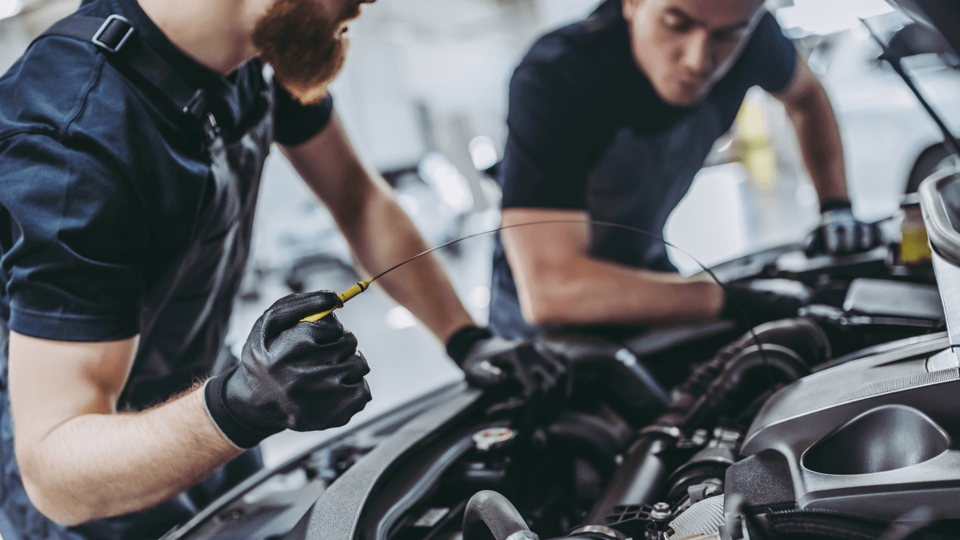 two mechanics doing an oil change on a car