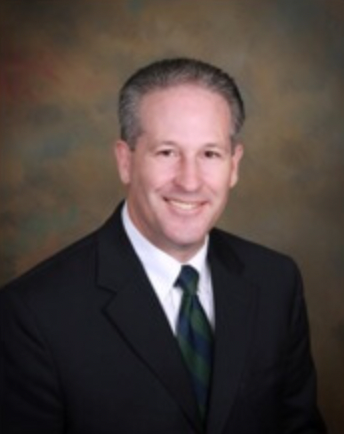 A man in a suit and tie is smiling for the camera