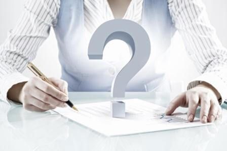 A woman is writing on a piece of paper next to a question mark.