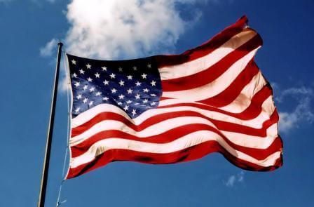 An american flag is waving in the wind against a blue sky
