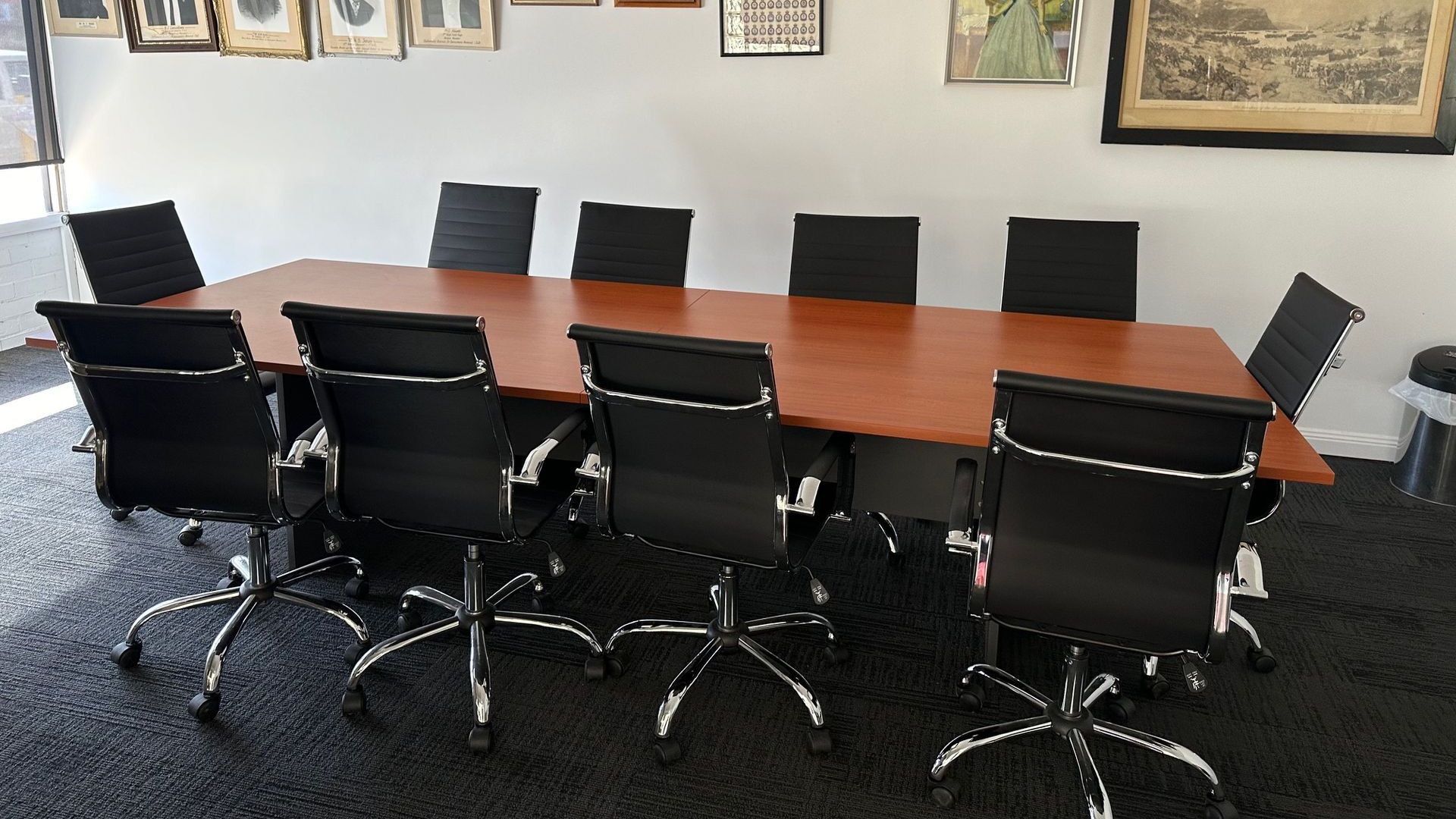 A conference room with a long table and black chairs