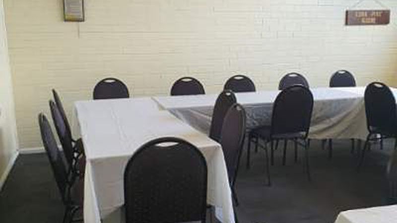 A room with tables and chairs and a sign on the wall.