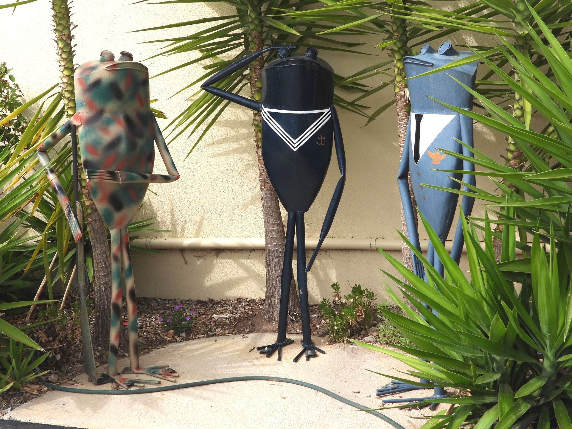 Three frogs are standing next to each other in a garden