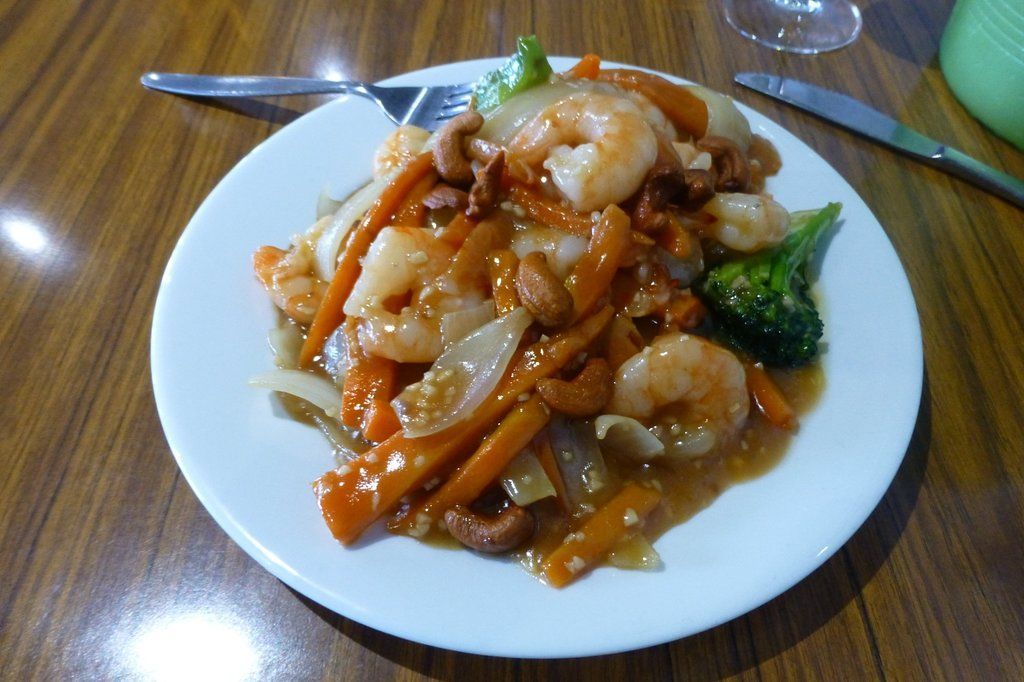 A white plate topped with prawns, carrots and broccoli