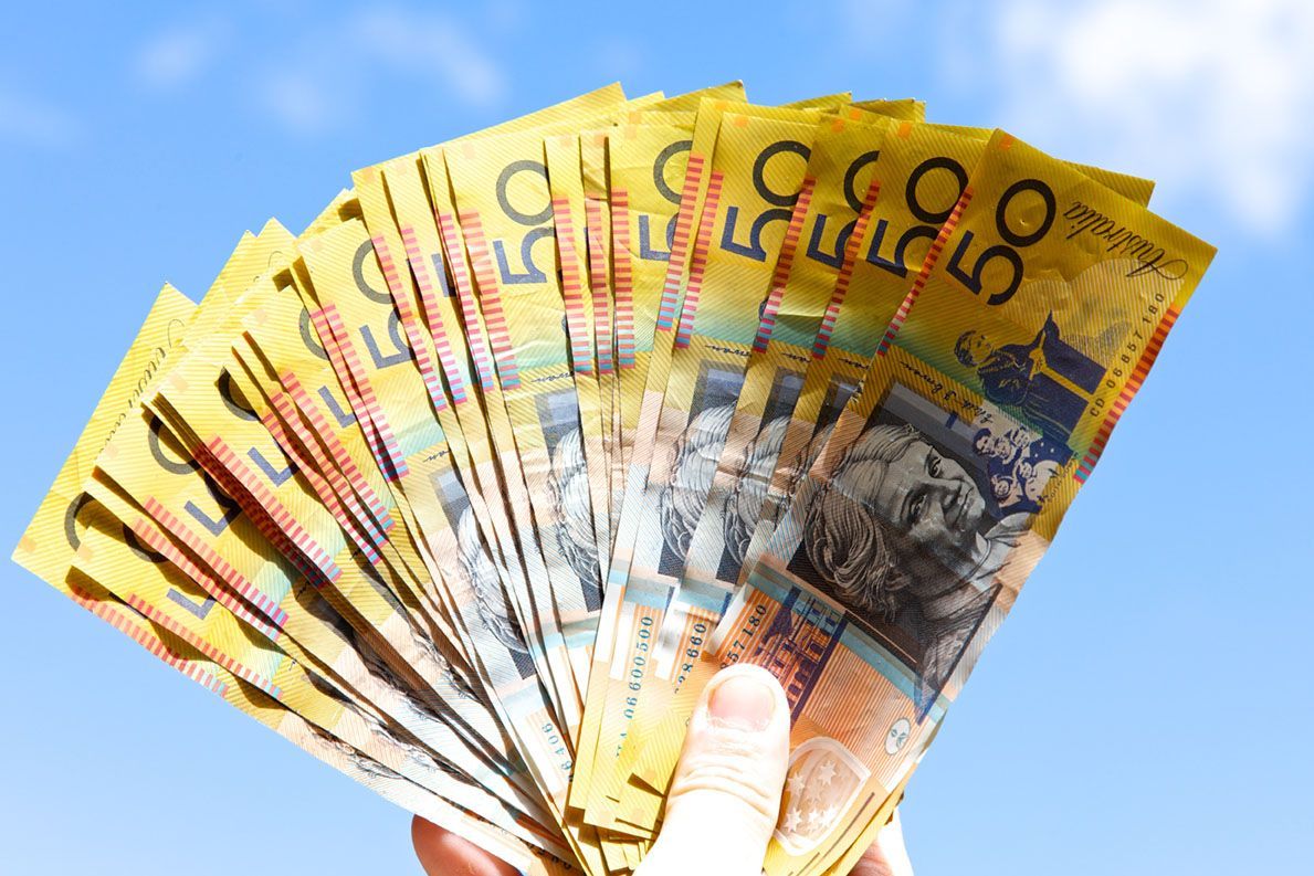 A person is holding a fan of Australian money