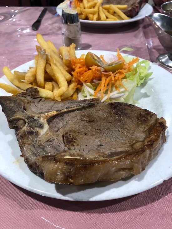 A white plate topped with a steak, salad and chips