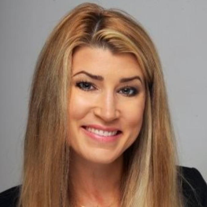 A woman with long blonde hair is smiling for the camera