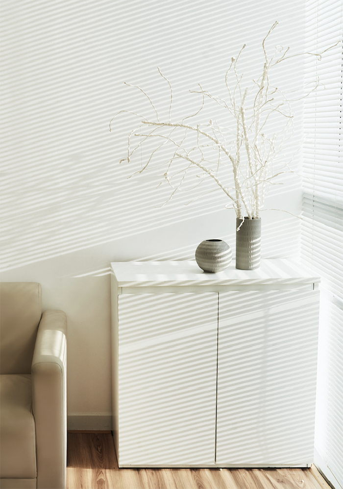 A white cabinet with two vases on top of it in a living room.