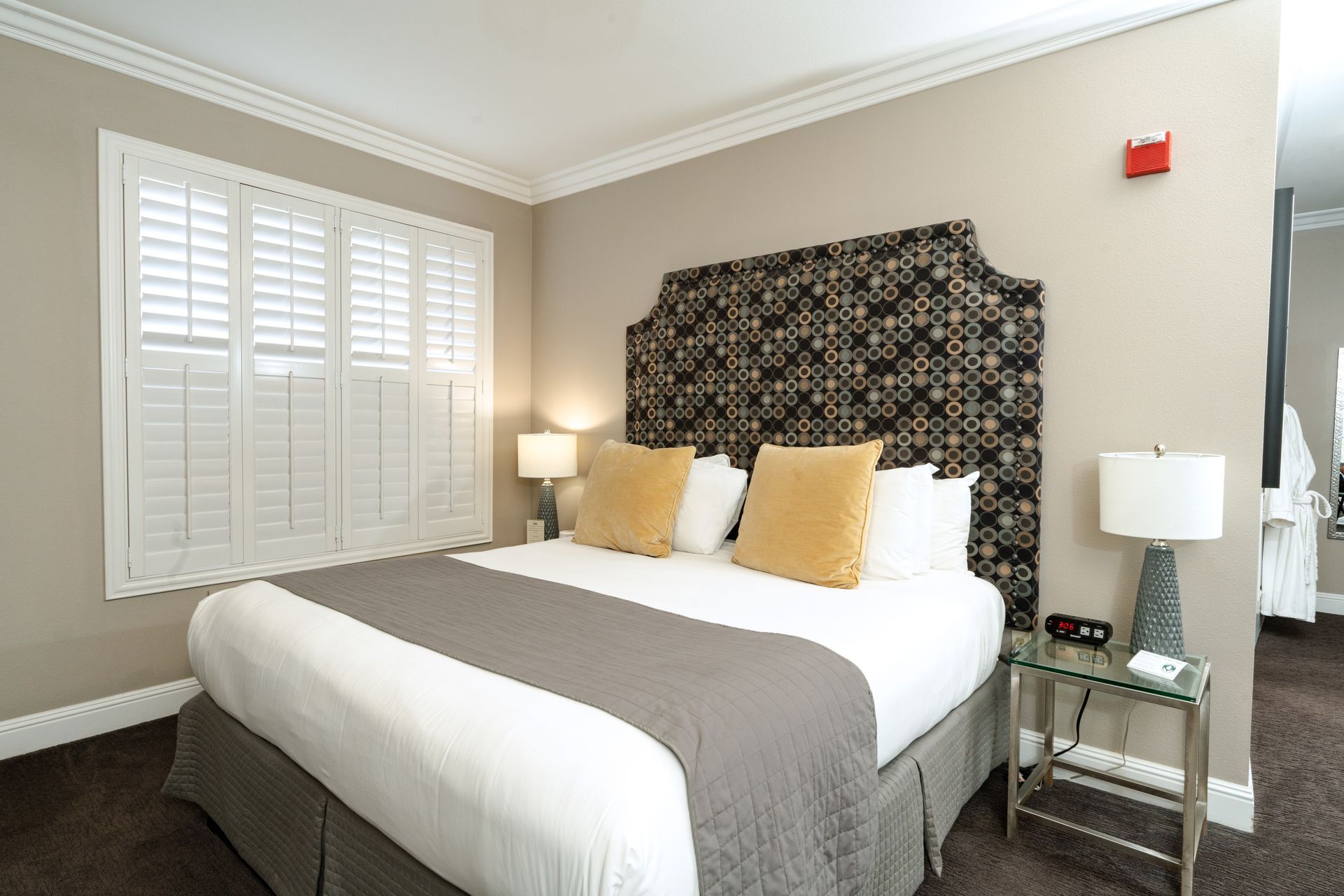 Bedroom with a large bed, decorative headboard, and window with shutters.