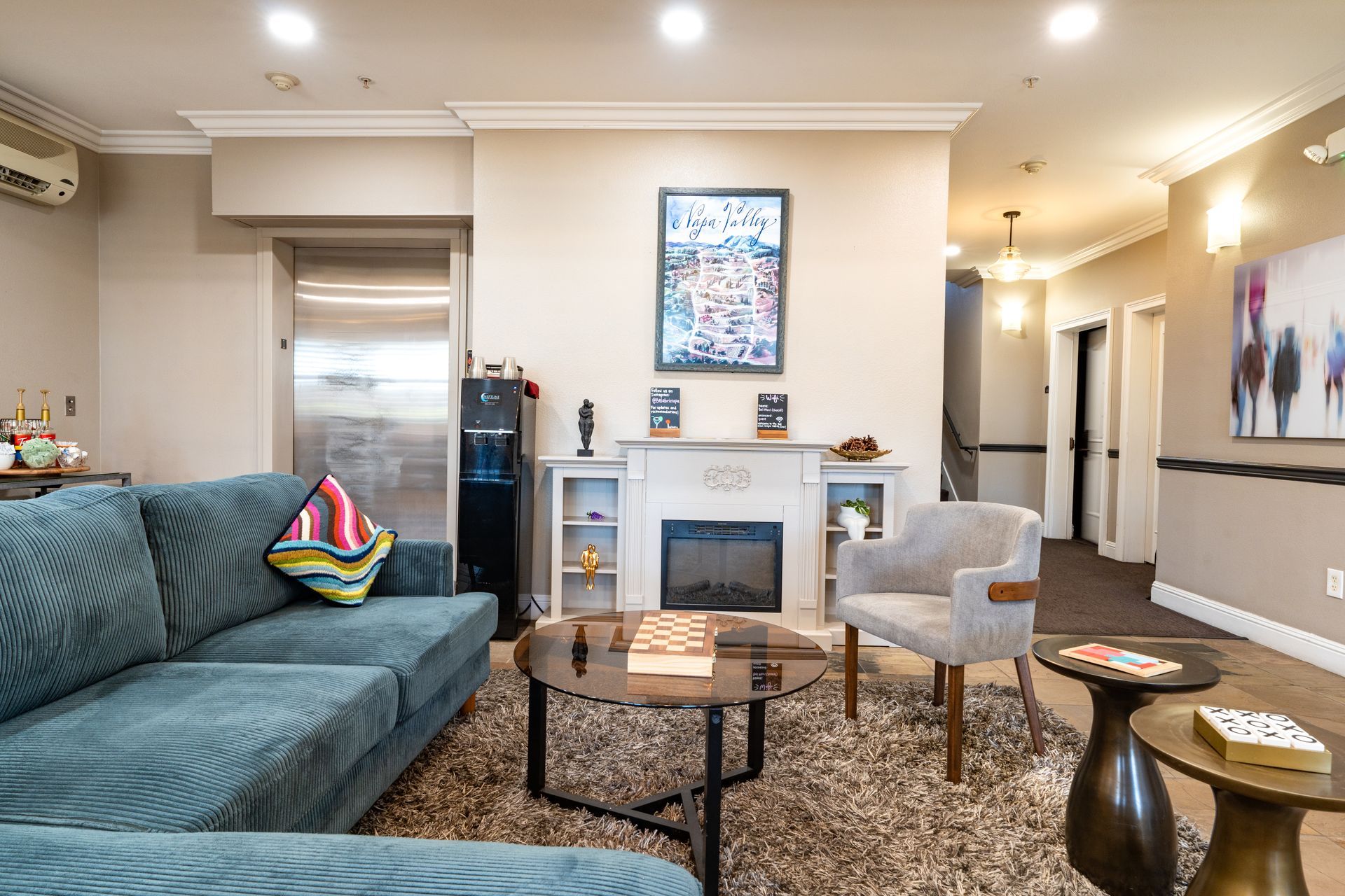 Living room with blue sofa, fireplace, and artwork; neutral walls and carpet.