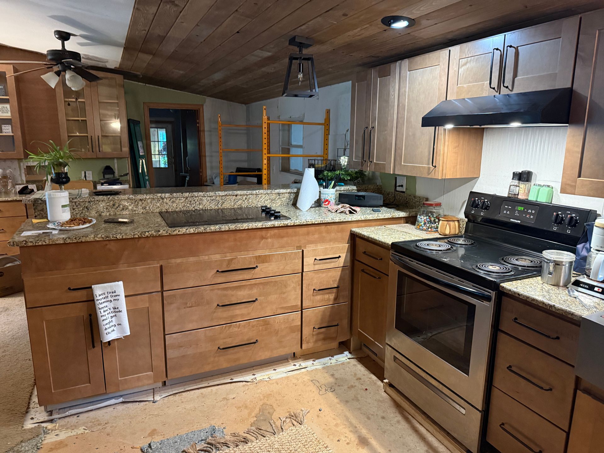 Modern kitchen with granite island, wood cabinets, stainless-steel stove, and vaulted wood ceiling