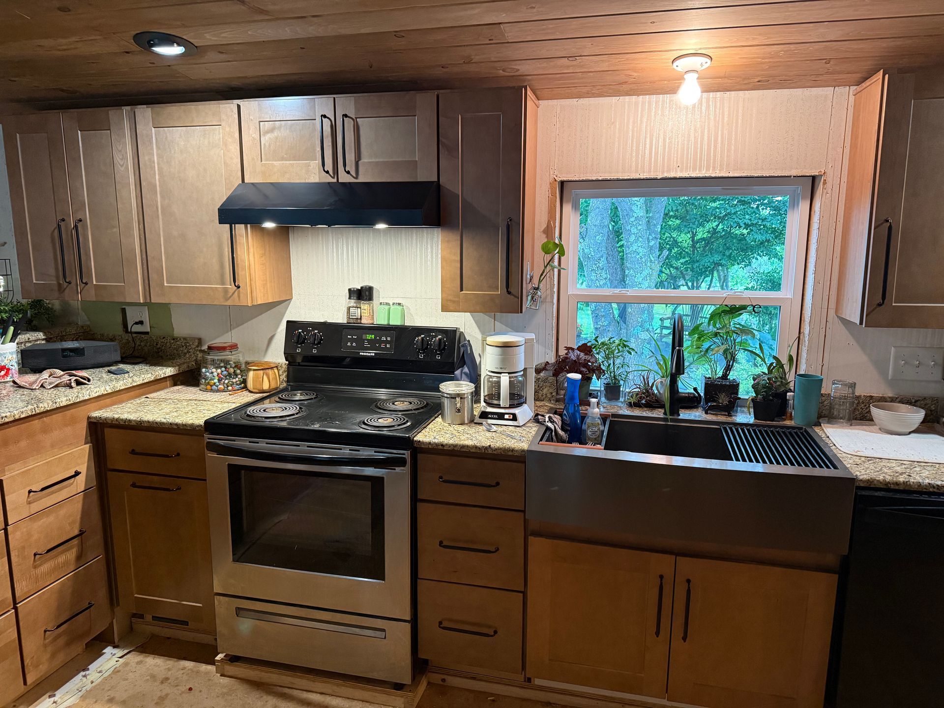 Cozy kitchen with stainless steel stove, wooden cabinets, and a window over the sink.