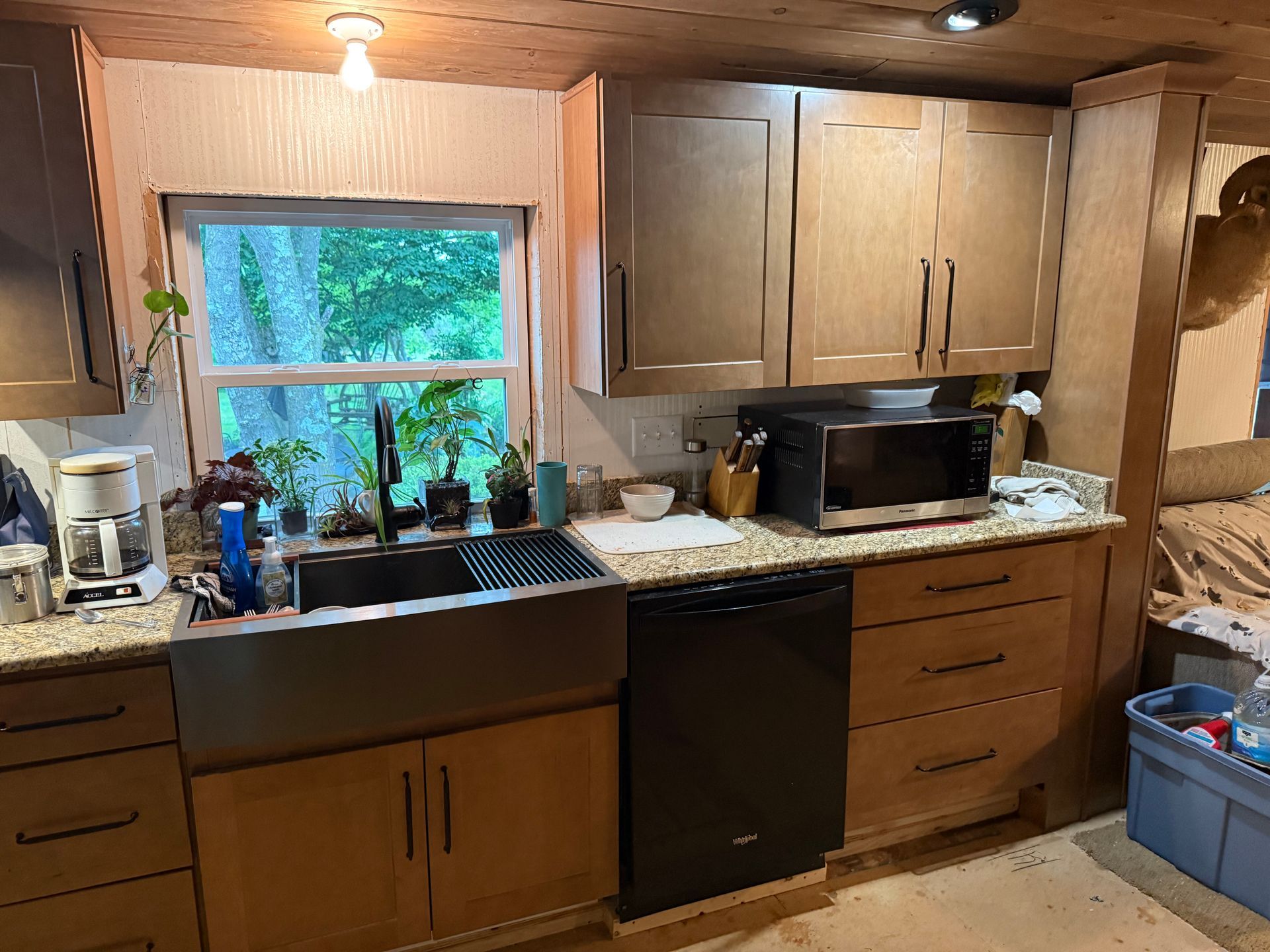 Cozy kitchen with wooden cabinets, double sink under a window, and counters with small appliances