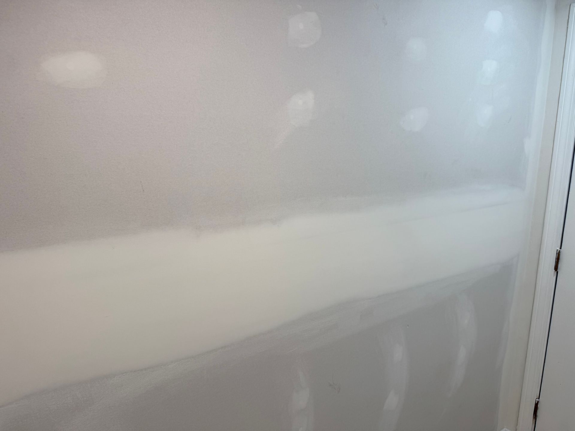 Hazy view of a white wall with bright reflections and a vertical edge on the right