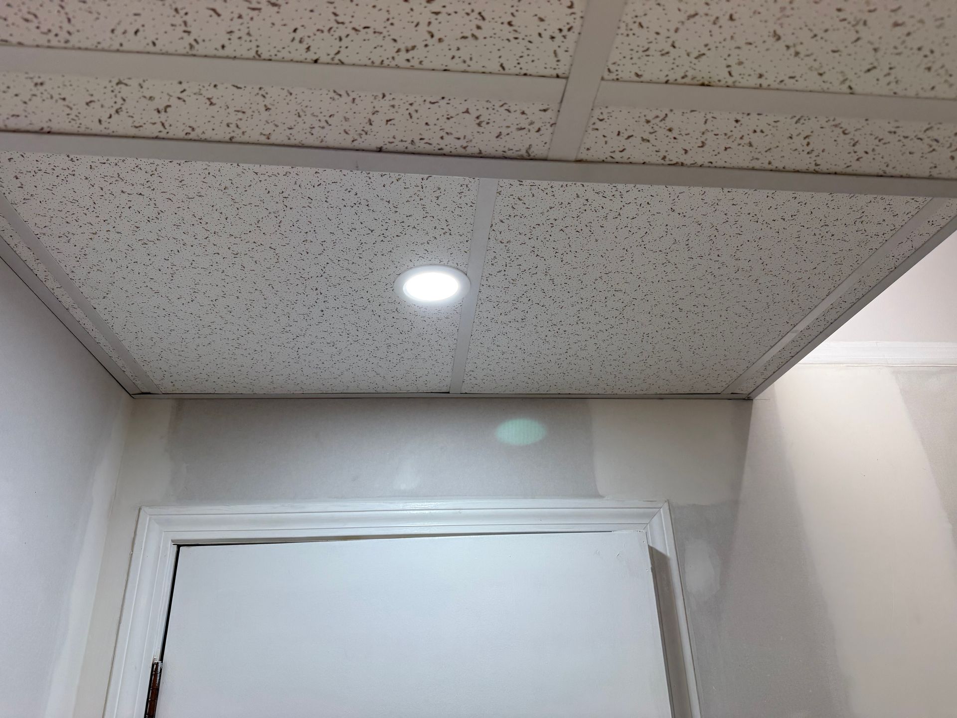 Office hallway ceiling with a recessed light above a white door