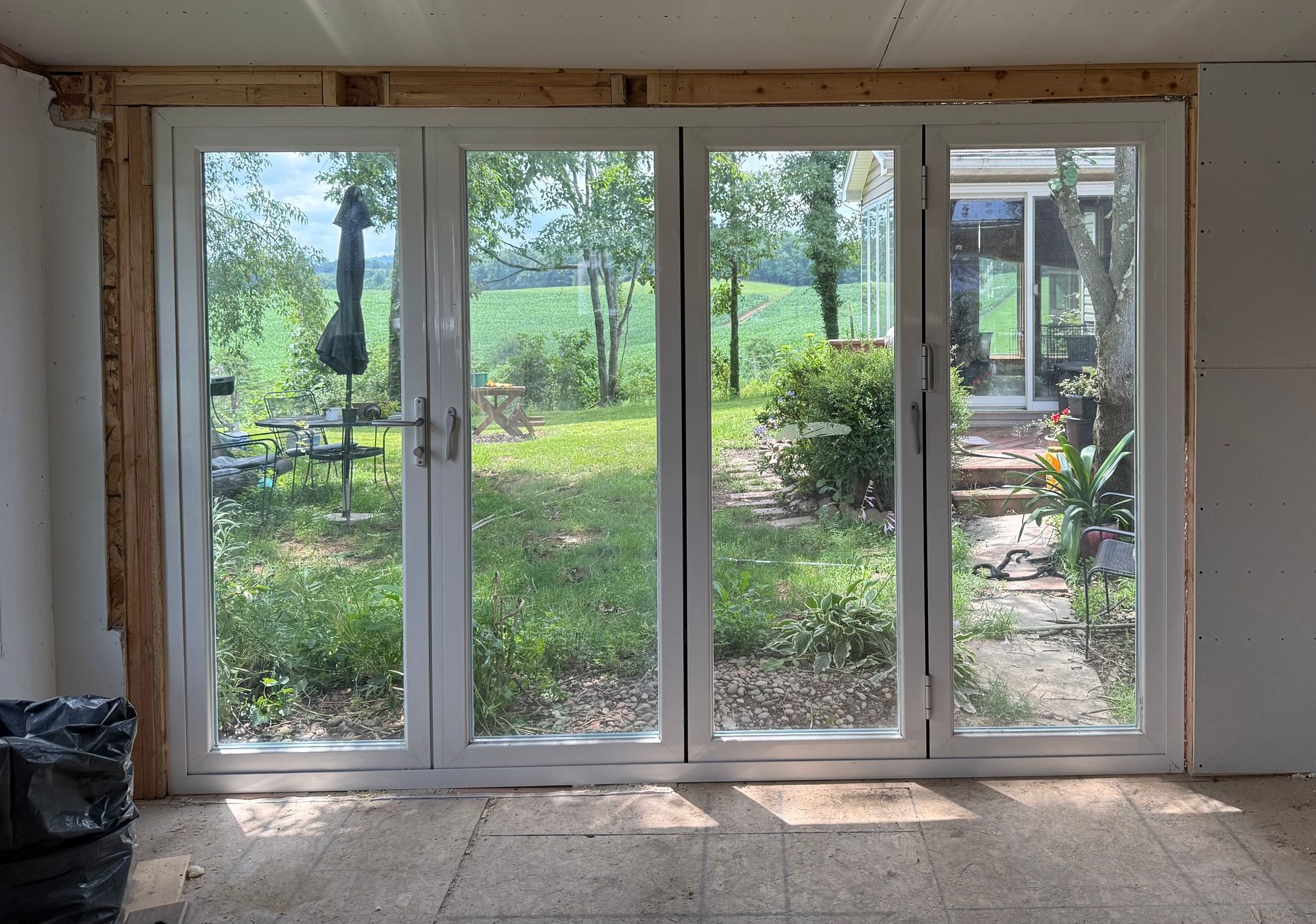 Sliding glass doors opening to a bright backyard with trees and a patio.