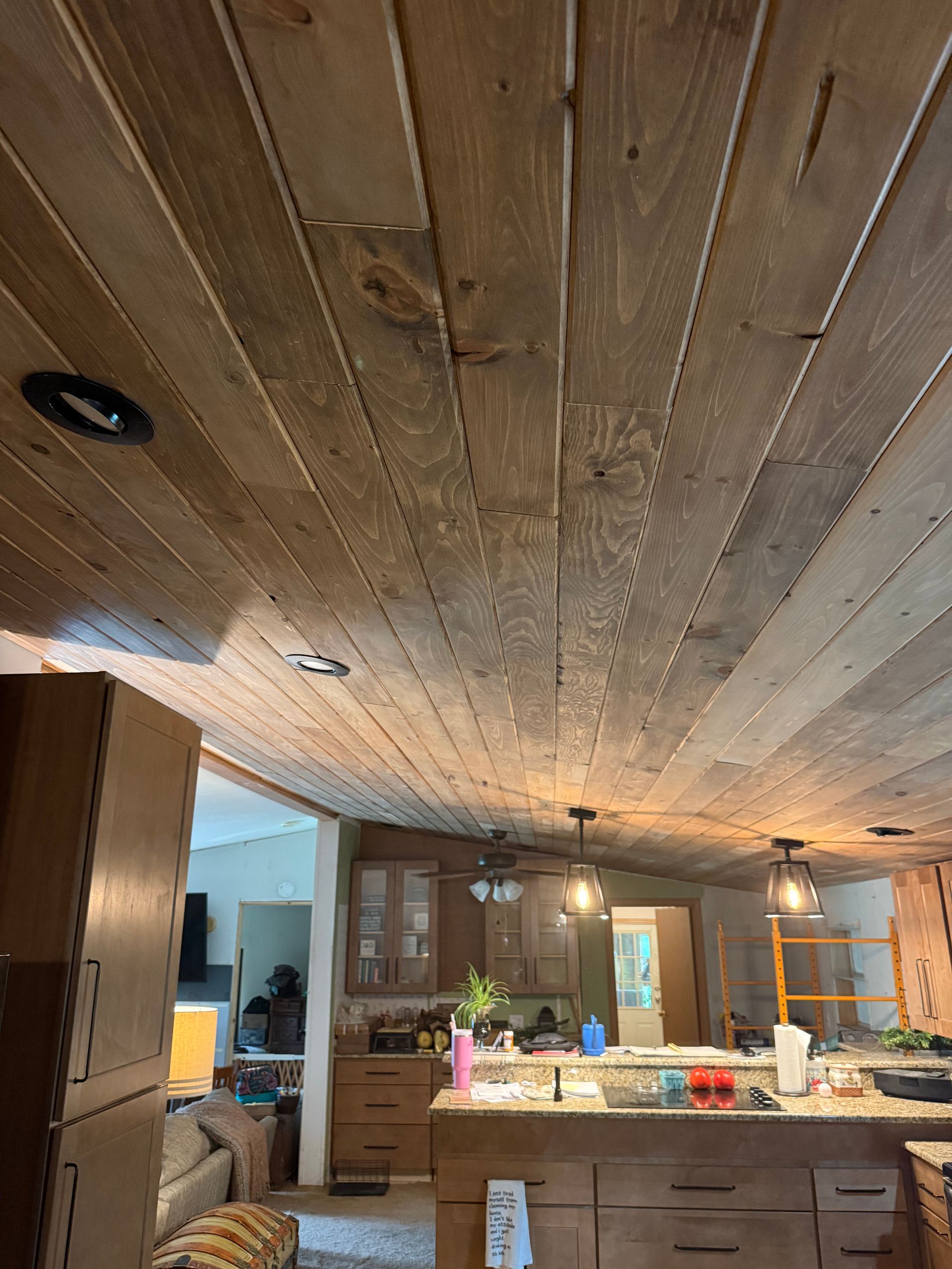 Rustic kitchen with wooden plank ceiling, island countertop, and hanging pendant lights