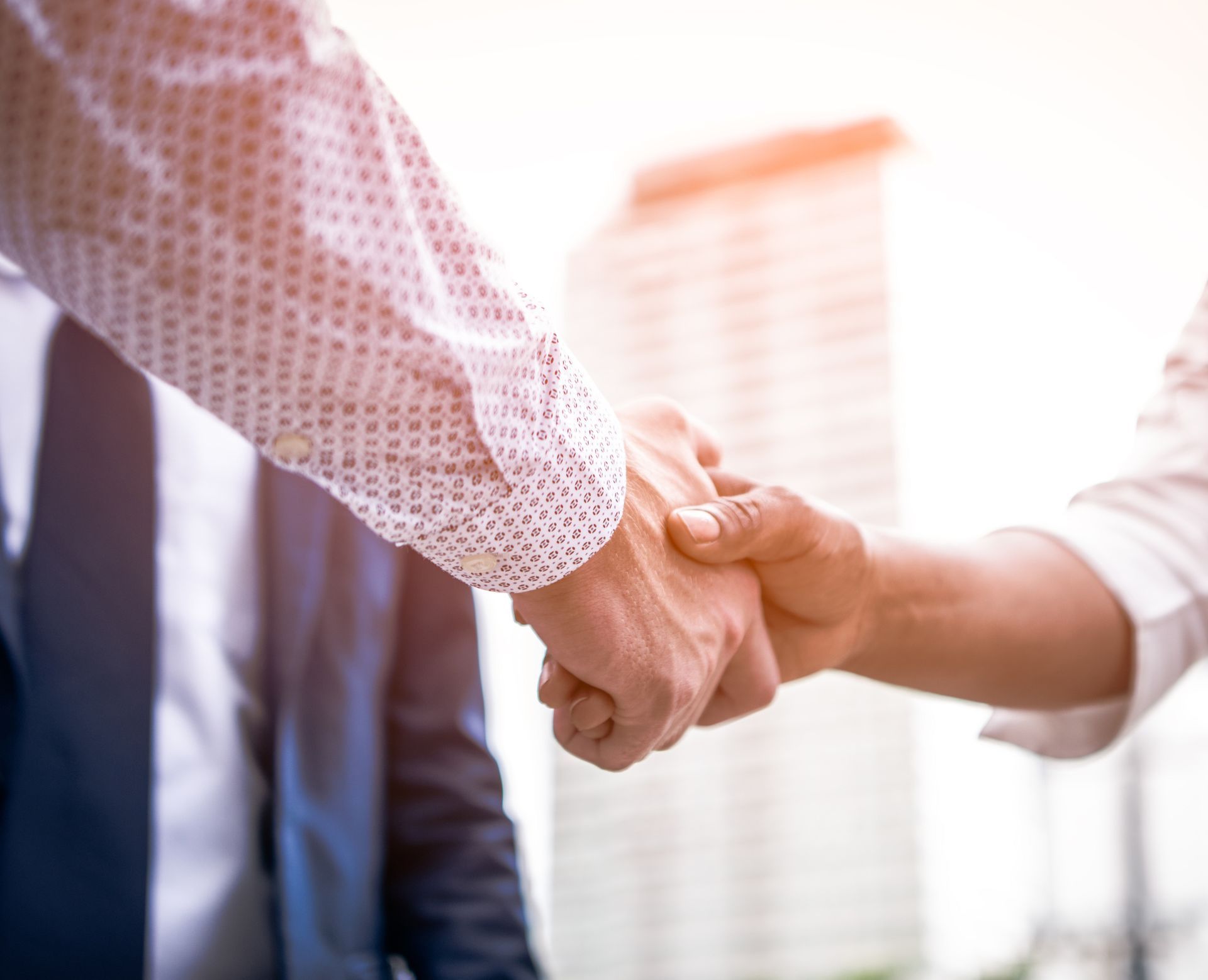 A man and a woman are shaking hands in front of a building.
