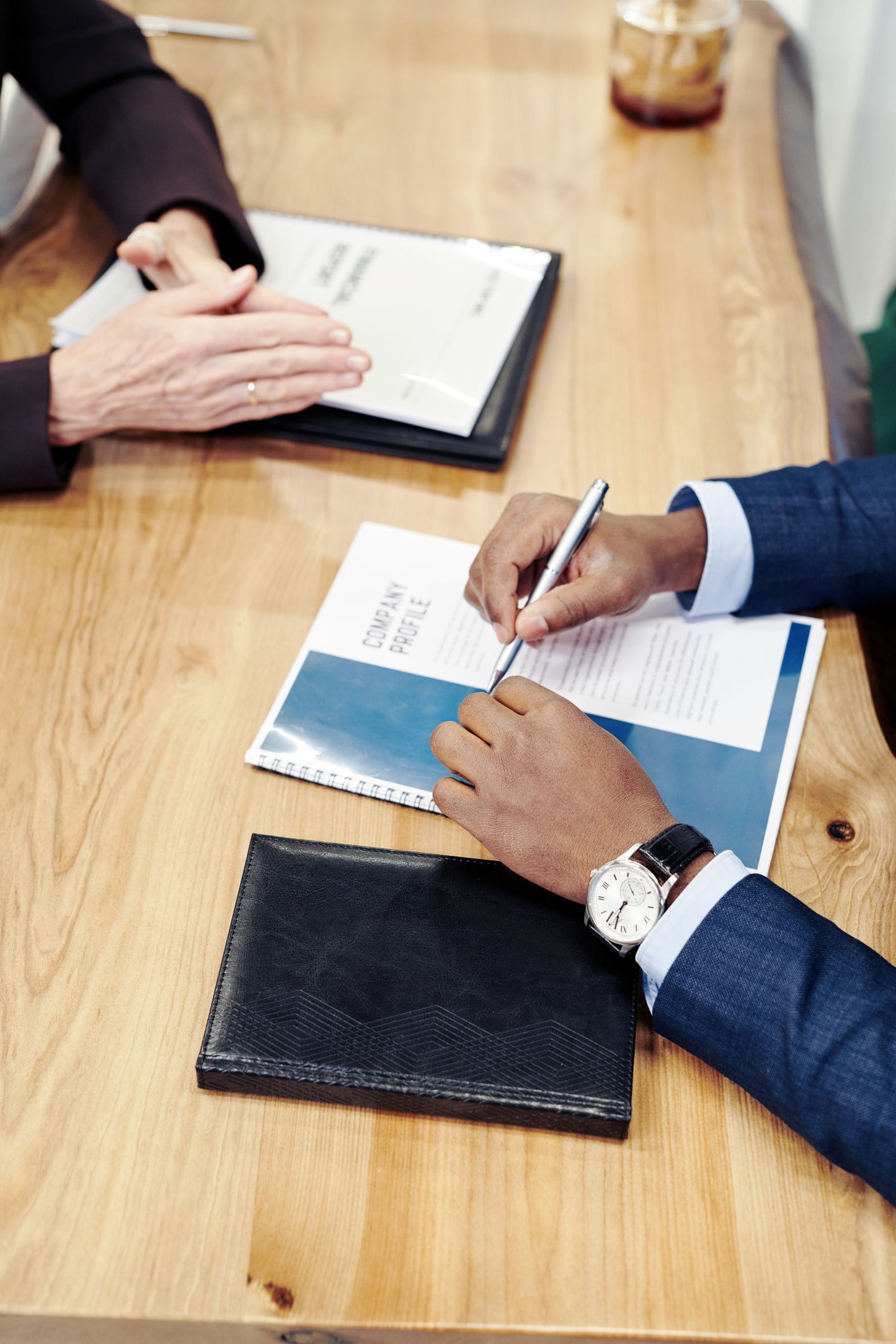 Two people are sitting at a table signing a document.
