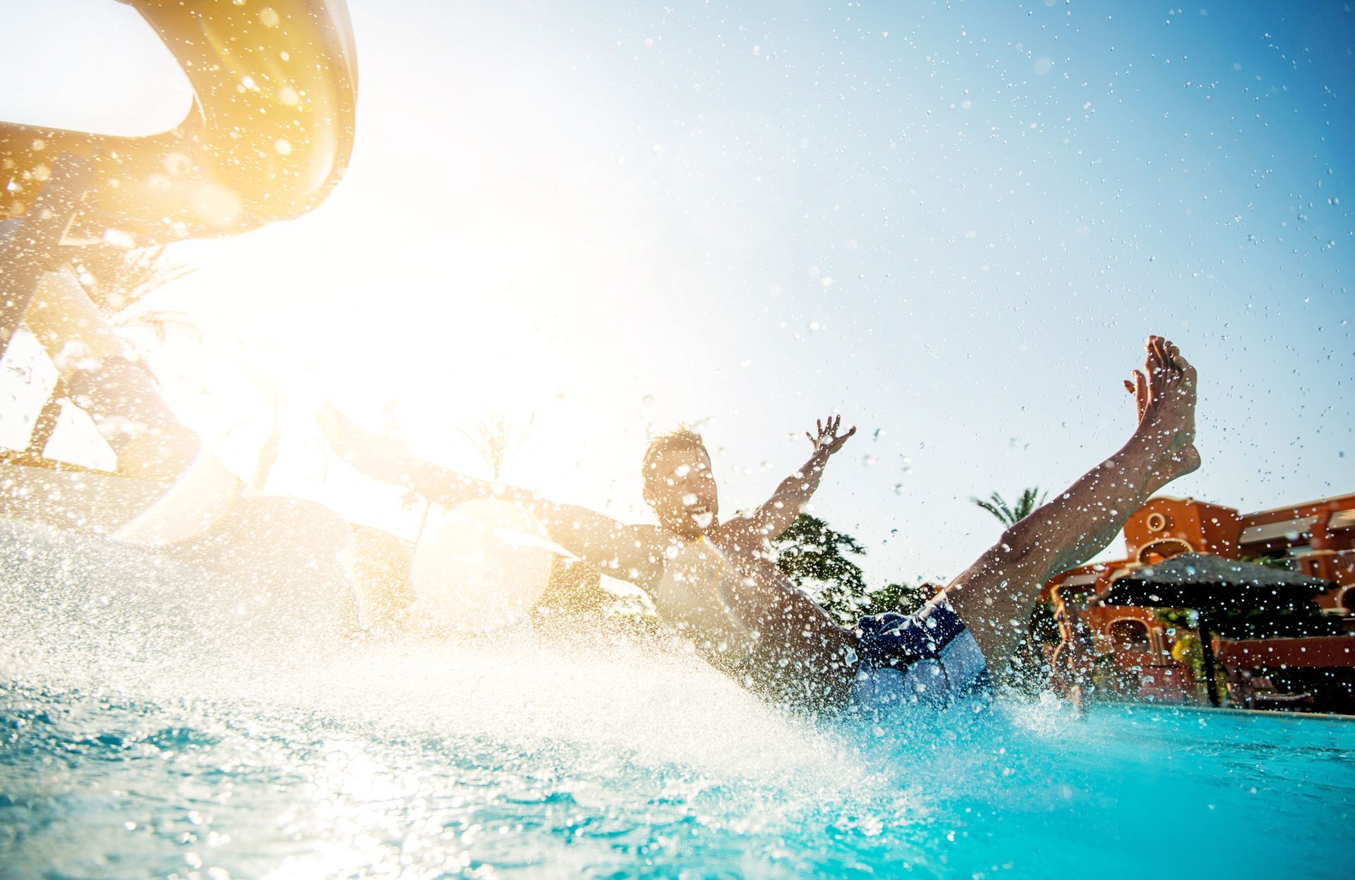 A man is sliding down a water slide in a swimming pool.