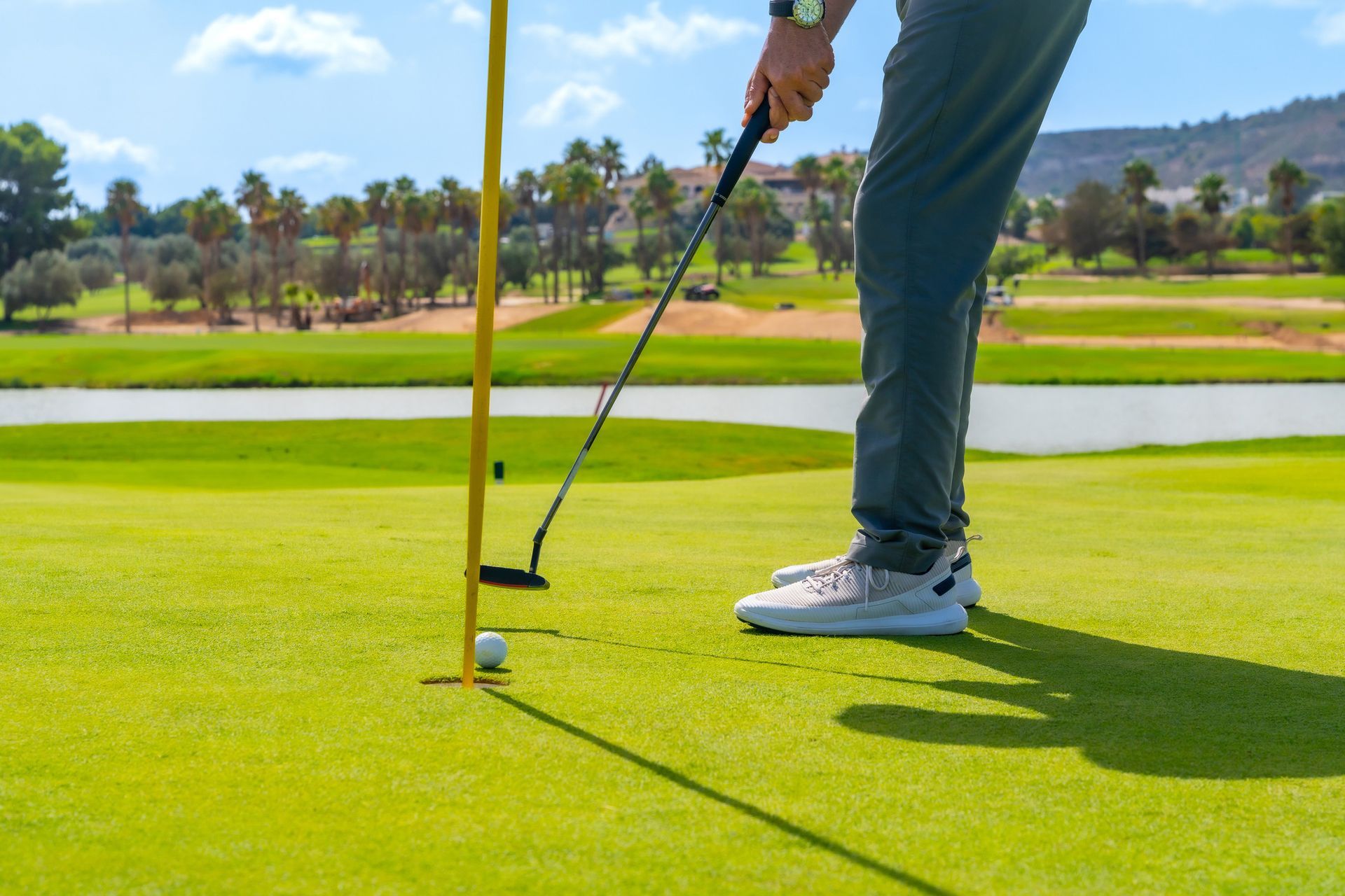 A man is putting a golf ball on a golf course.