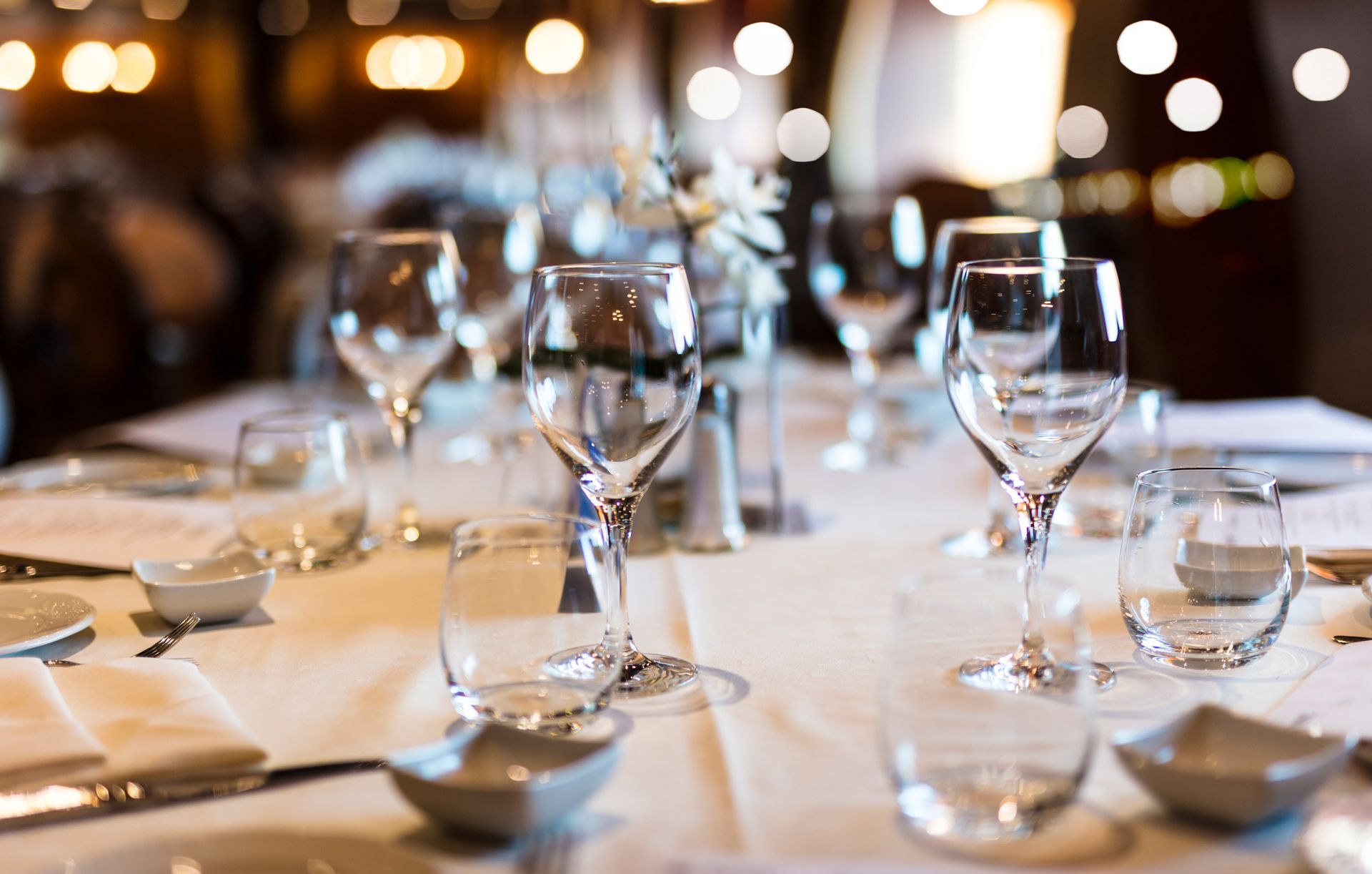 A table set for a dinner party with wine glasses, plates, and silverware.
