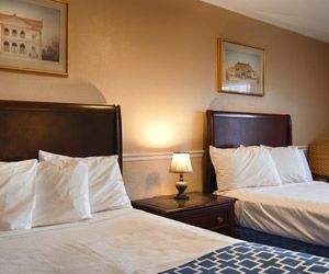 A hotel room with two beds and a lamp.
