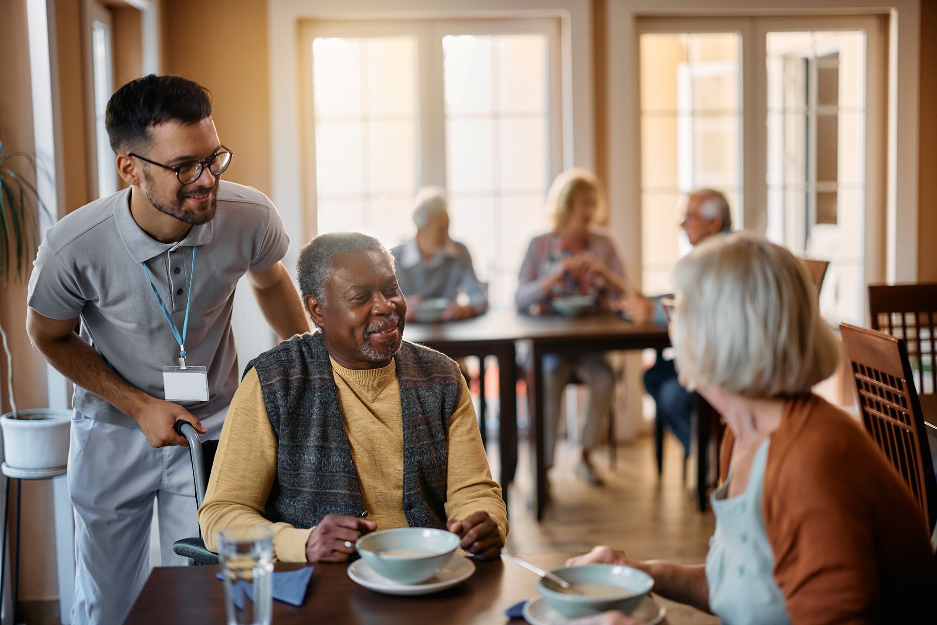 Healthcare worker and senior people during lunch at an assisted living home.