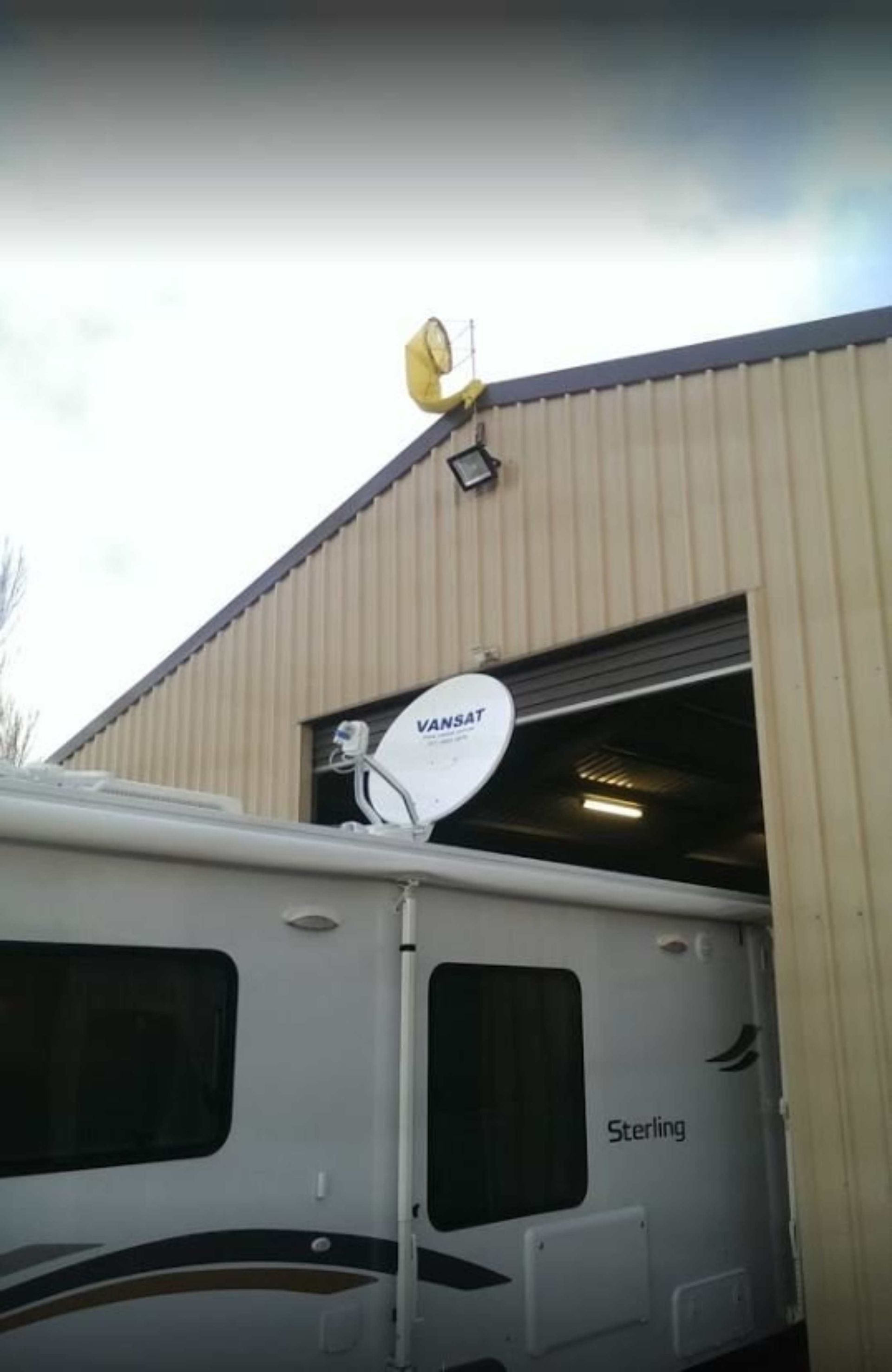 A satellite dish is mounted on the side of a RV.
