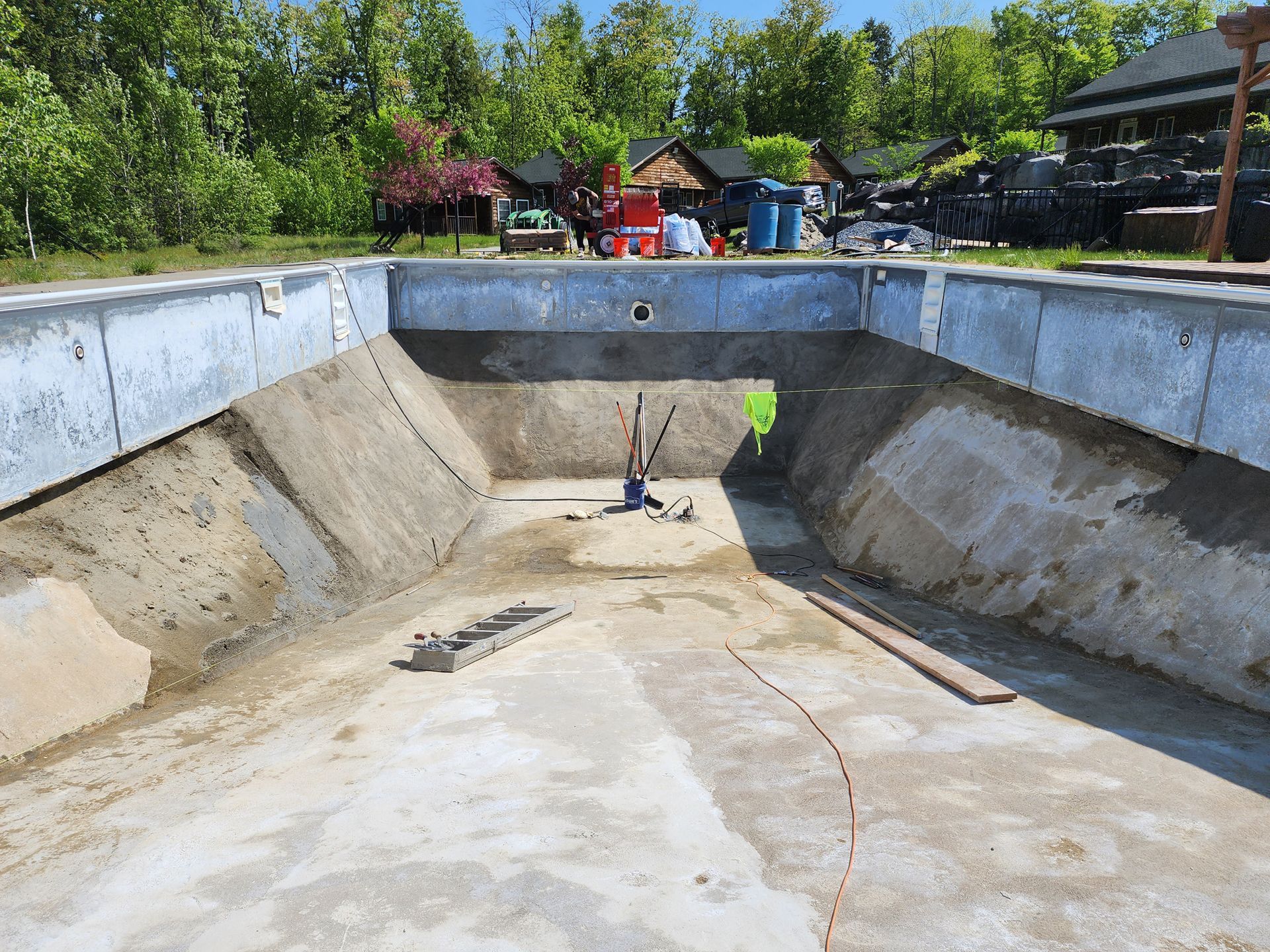 A large concrete pool is being built in a backyard.