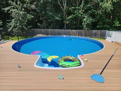 A large swimming pool is sitting on top of a wooden deck.