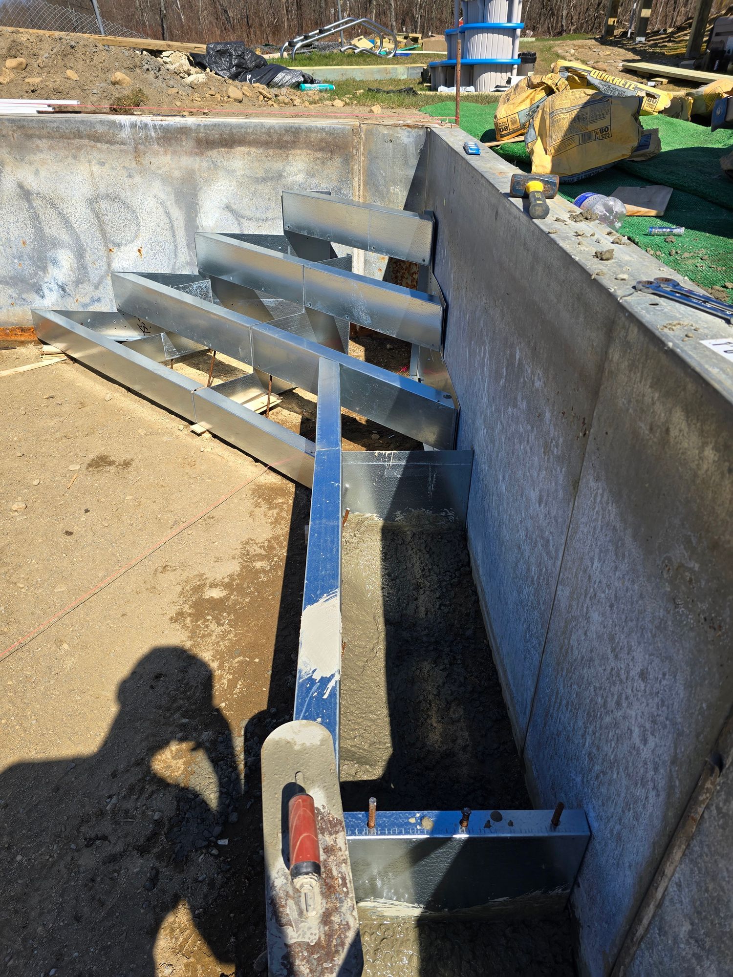 A metal staircase is being built into a concrete wall.