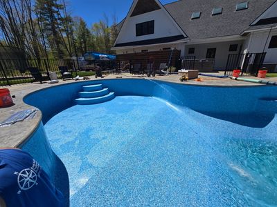 A large swimming pool is being built in front of a house.