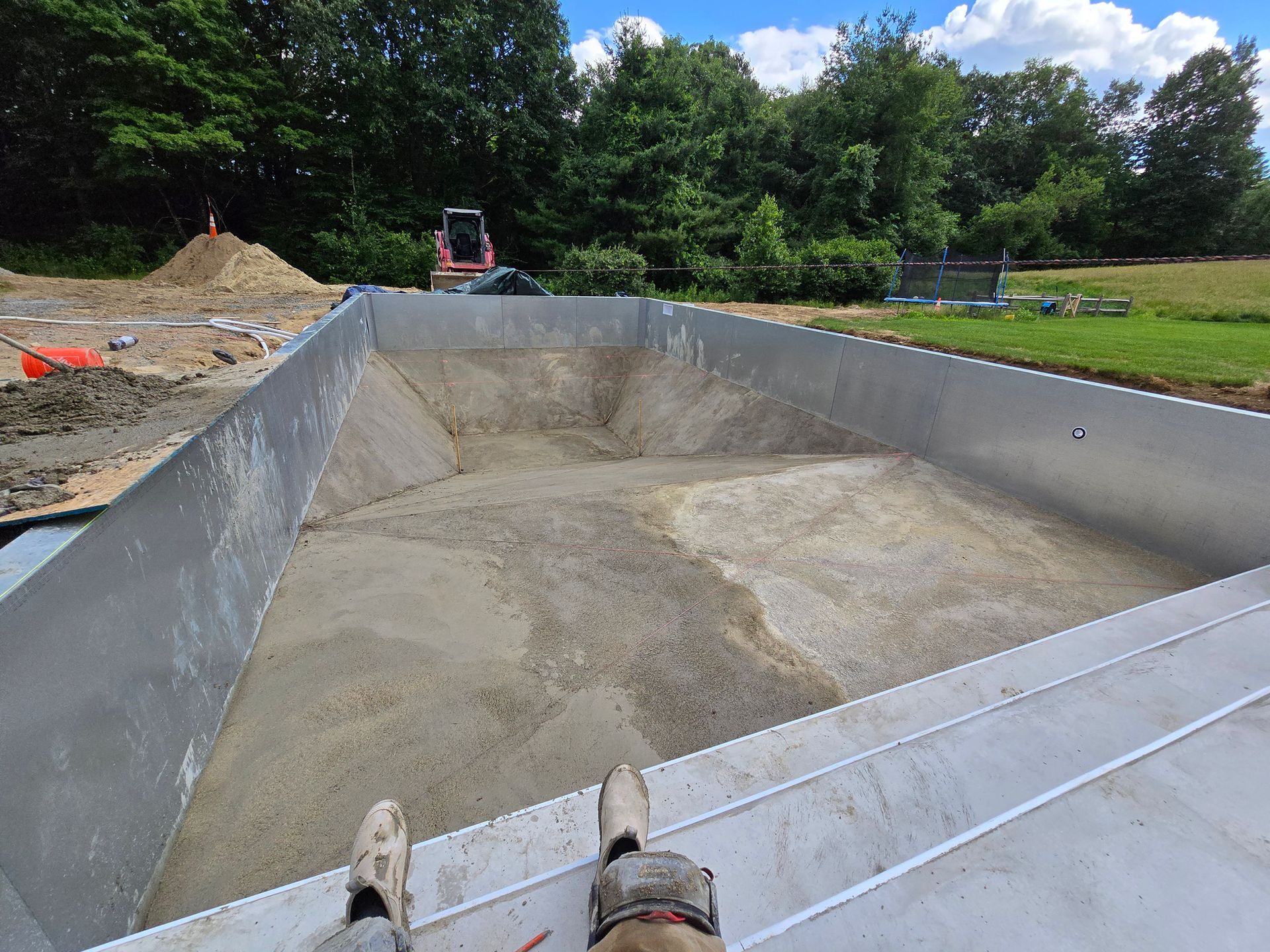 A person is laying on the side of a truck filled with dirt.