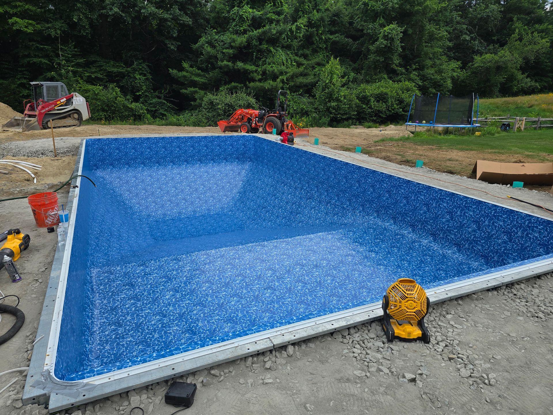 A large blue swimming pool is being built in a backyard.