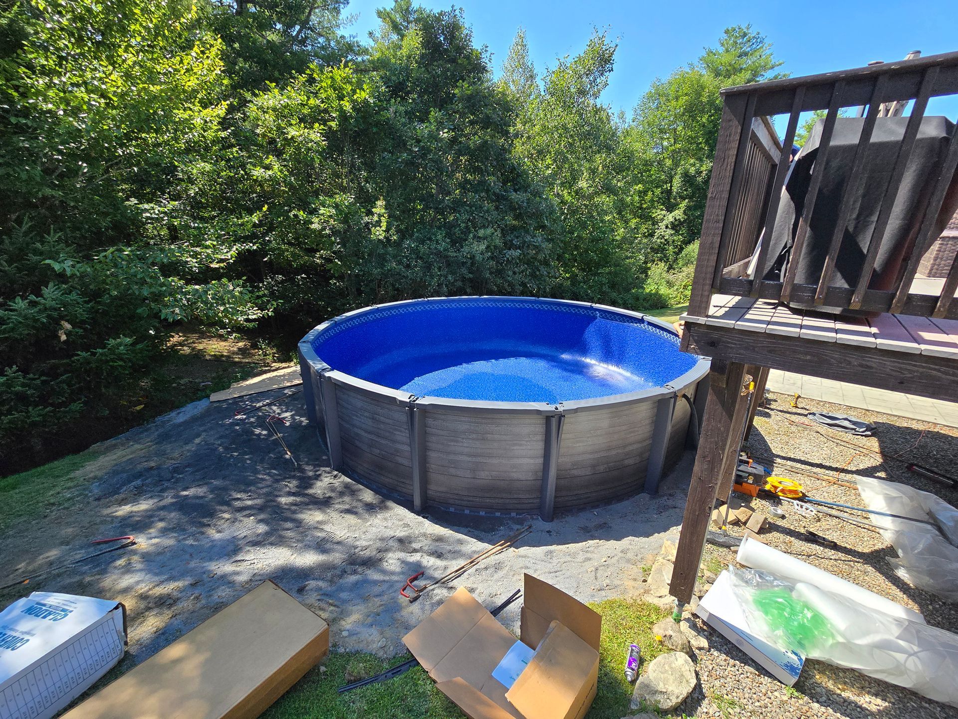 A swimming pool is being built in a backyard next to a deck.