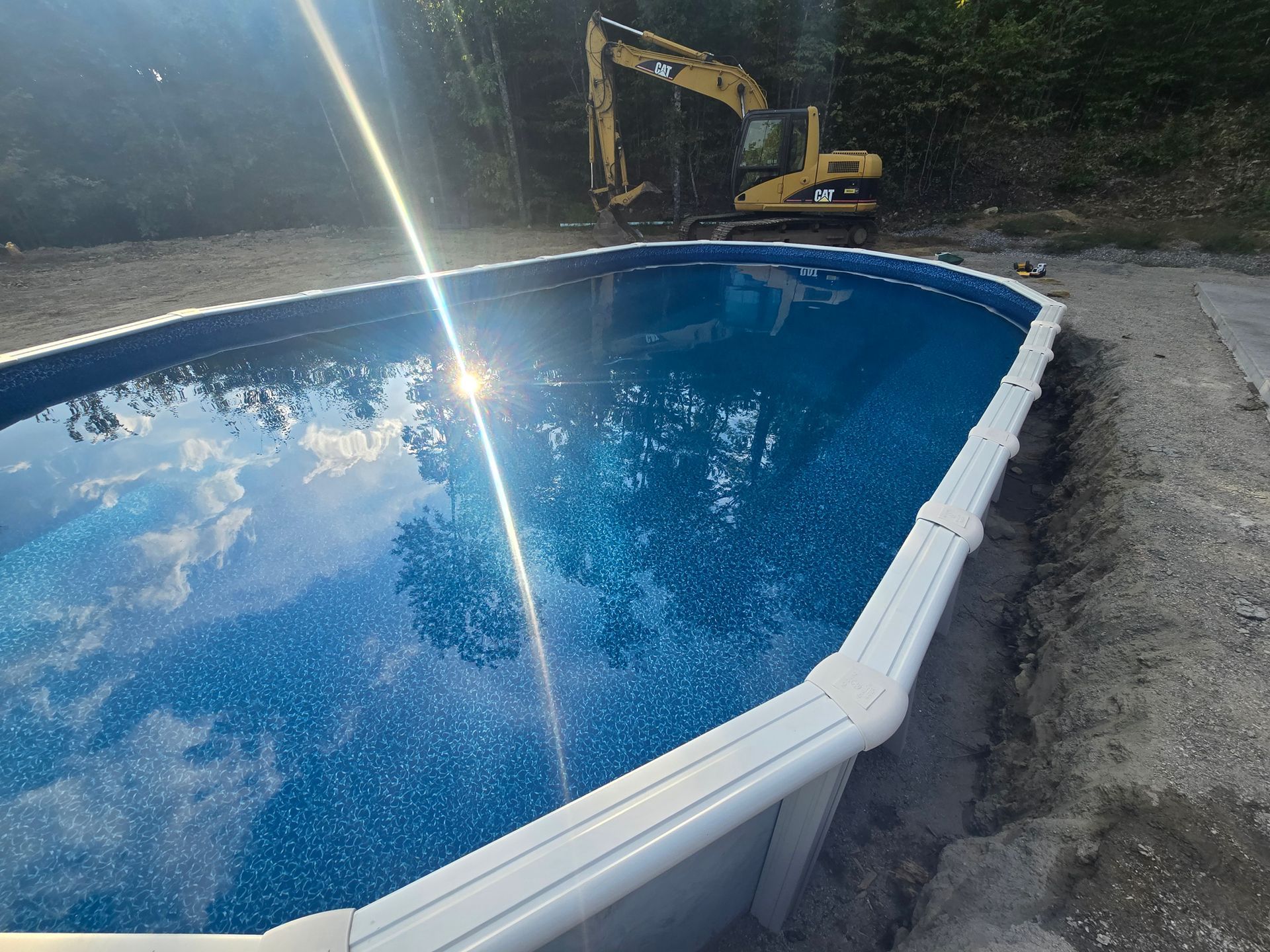 A large swimming pool with a yellow excavator in the background