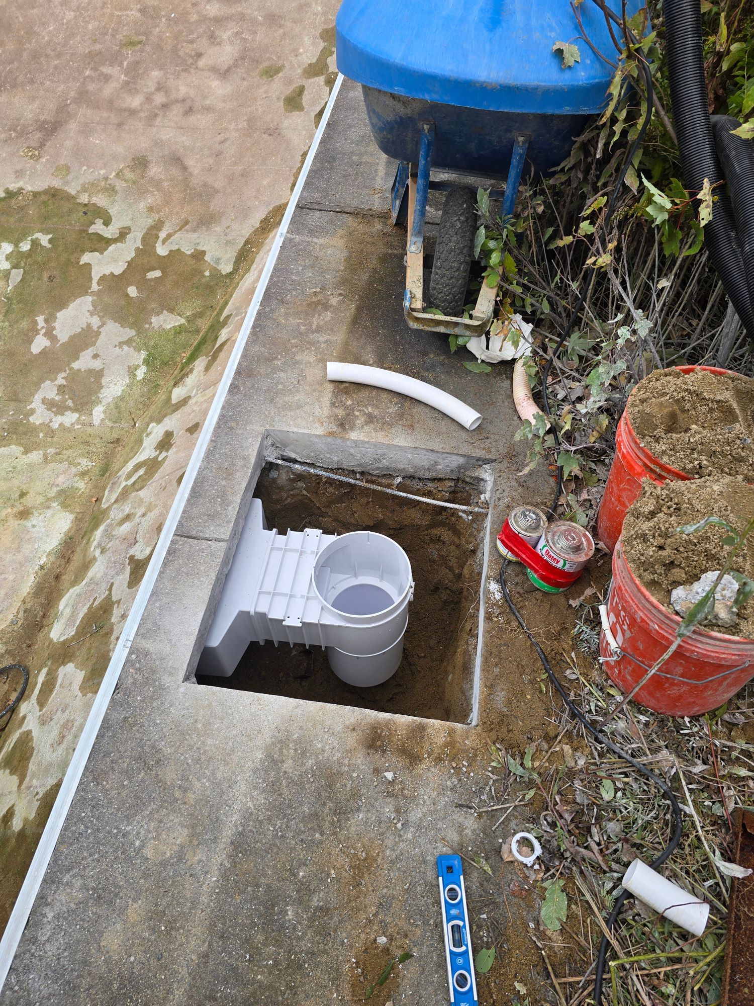 A wheelbarrow is sitting next to a hole in the ground.